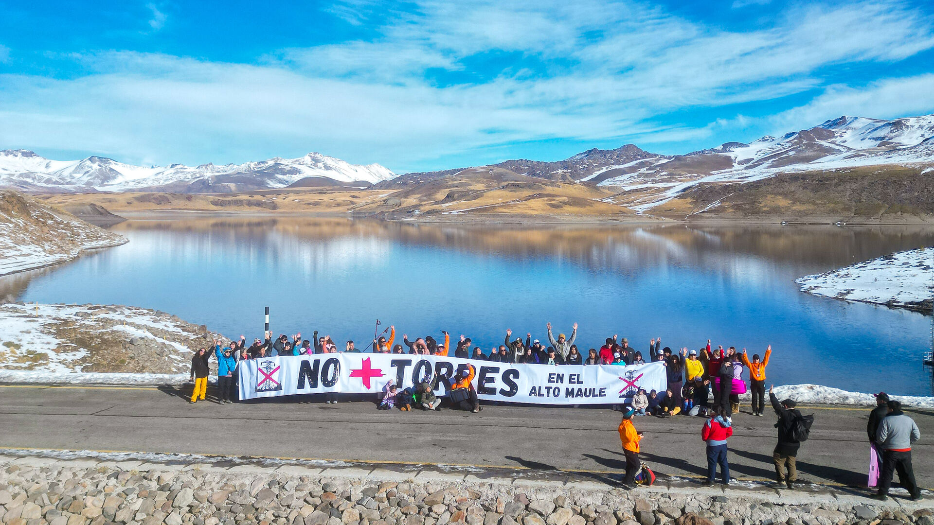 Comunidad reunida en la Laguna del Maule con el lienzo No + Torres en el Alto Maule